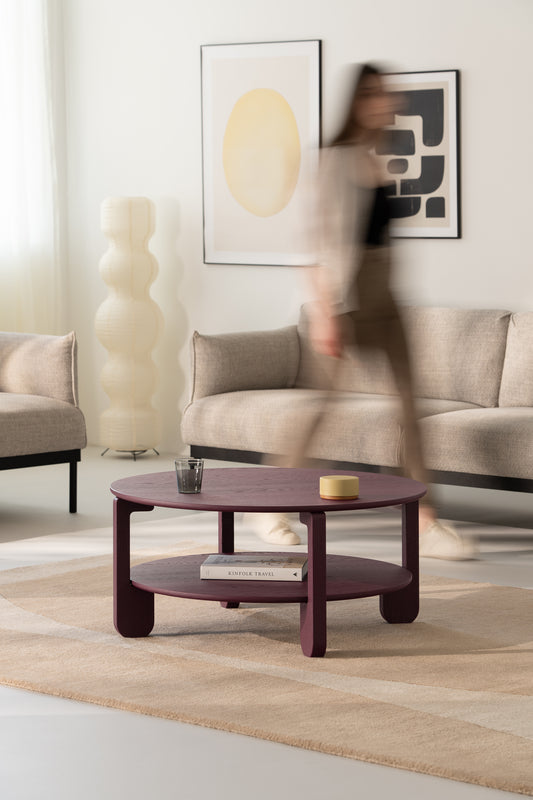 NOON round coffee table in burgundy solid oak, seen from above on a light wooden floor