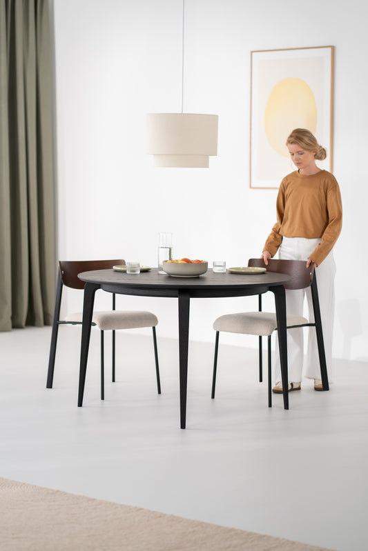 Black solid oak YUKI round dining table seen from above, showing wood grain through matte finish