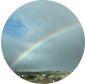 A rainbow against a cloudy sky over a landscape.