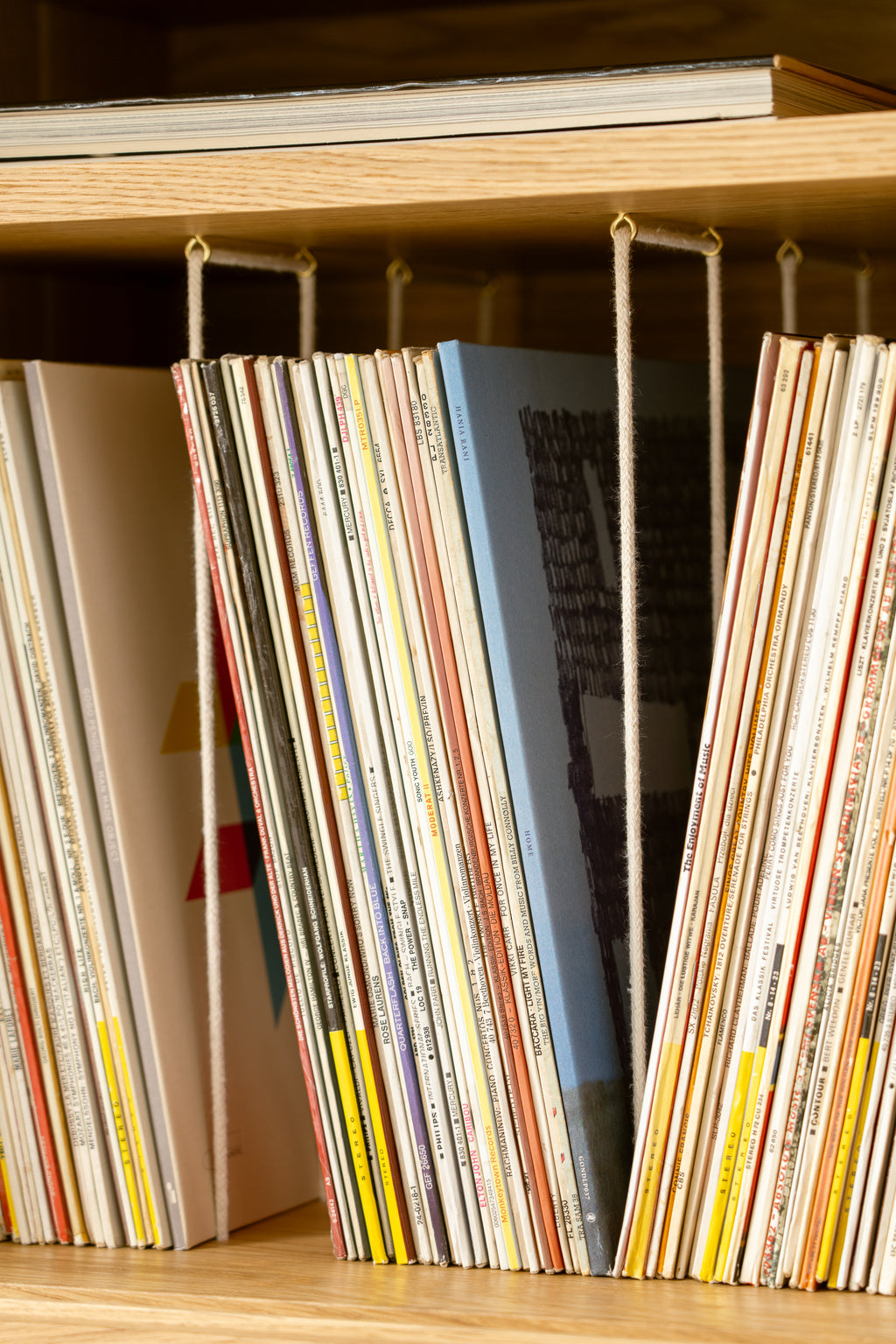 A shelf with vinyl records arranged vertically on a wooden shelf.