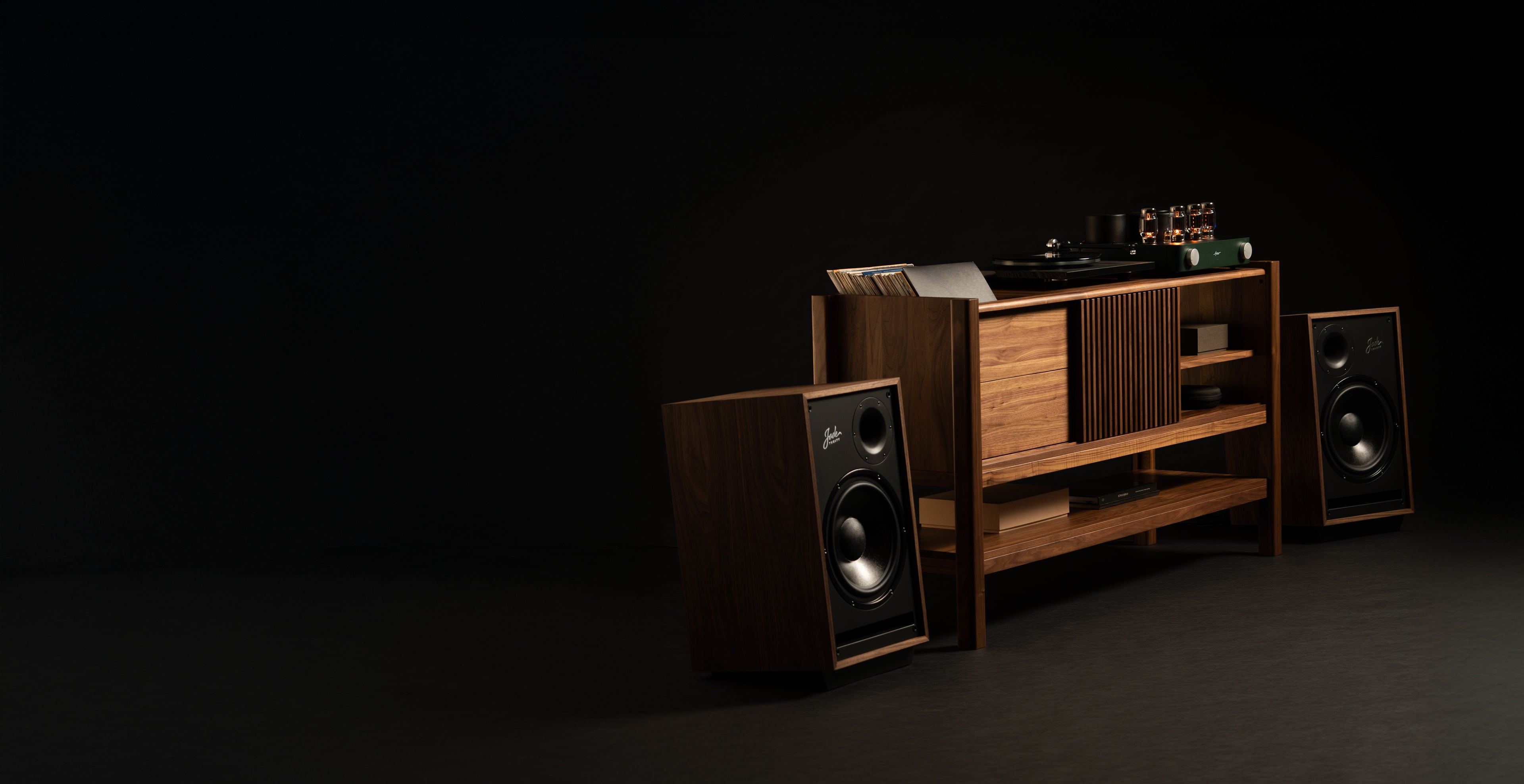 A vintage-style audio setup featuring a wooden cabinet with a record player and tube amplifier on top. Vinyl records are partially visible on the left side of the cabinet. Two large wooden speakers flank the cabinet on either side, all set against a dark background.