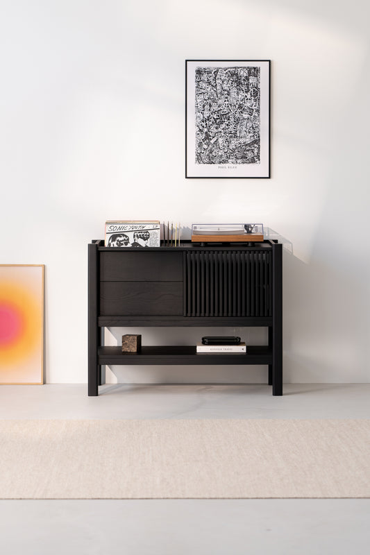 Black cabinet with vinyl records and a turntable, framed art above, and gradient artwork on the floor.