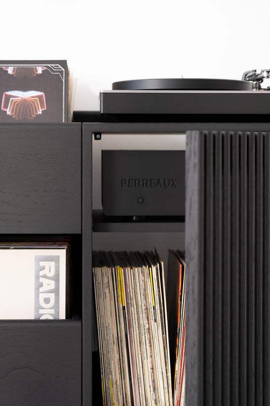 Vinyl records and a turntable on a black shelf with "Perreaux" audio equipment.