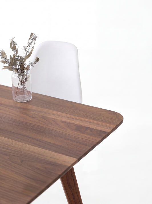 A wooden mid-century modern table with tapered legs against a white background.