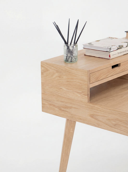 Wooden desk with a jar of black sticks and books on top.