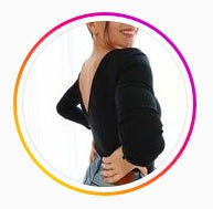 A person in a black top with an open back, with hands on their hips.