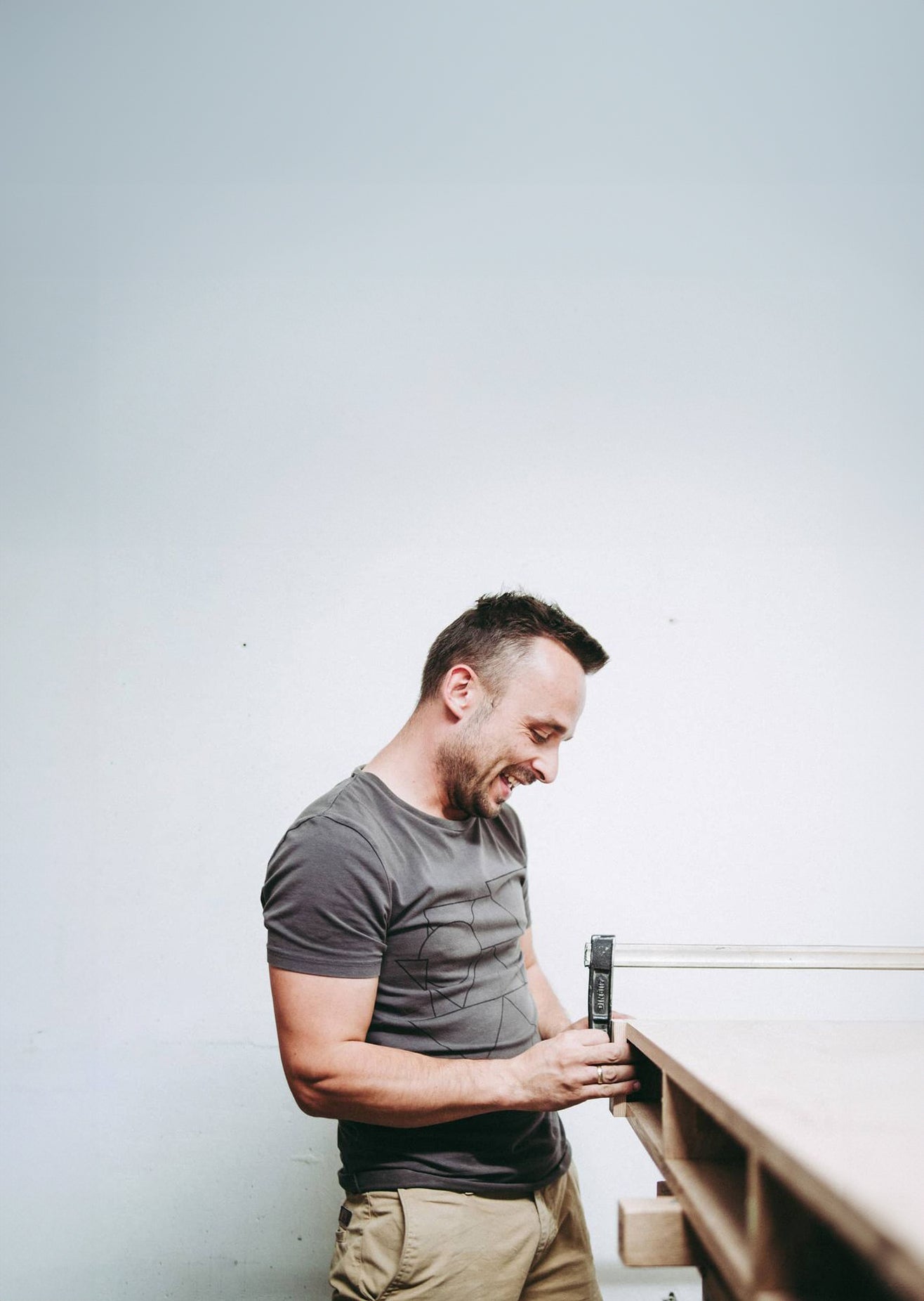 A man working with a clamp at a wooden table.