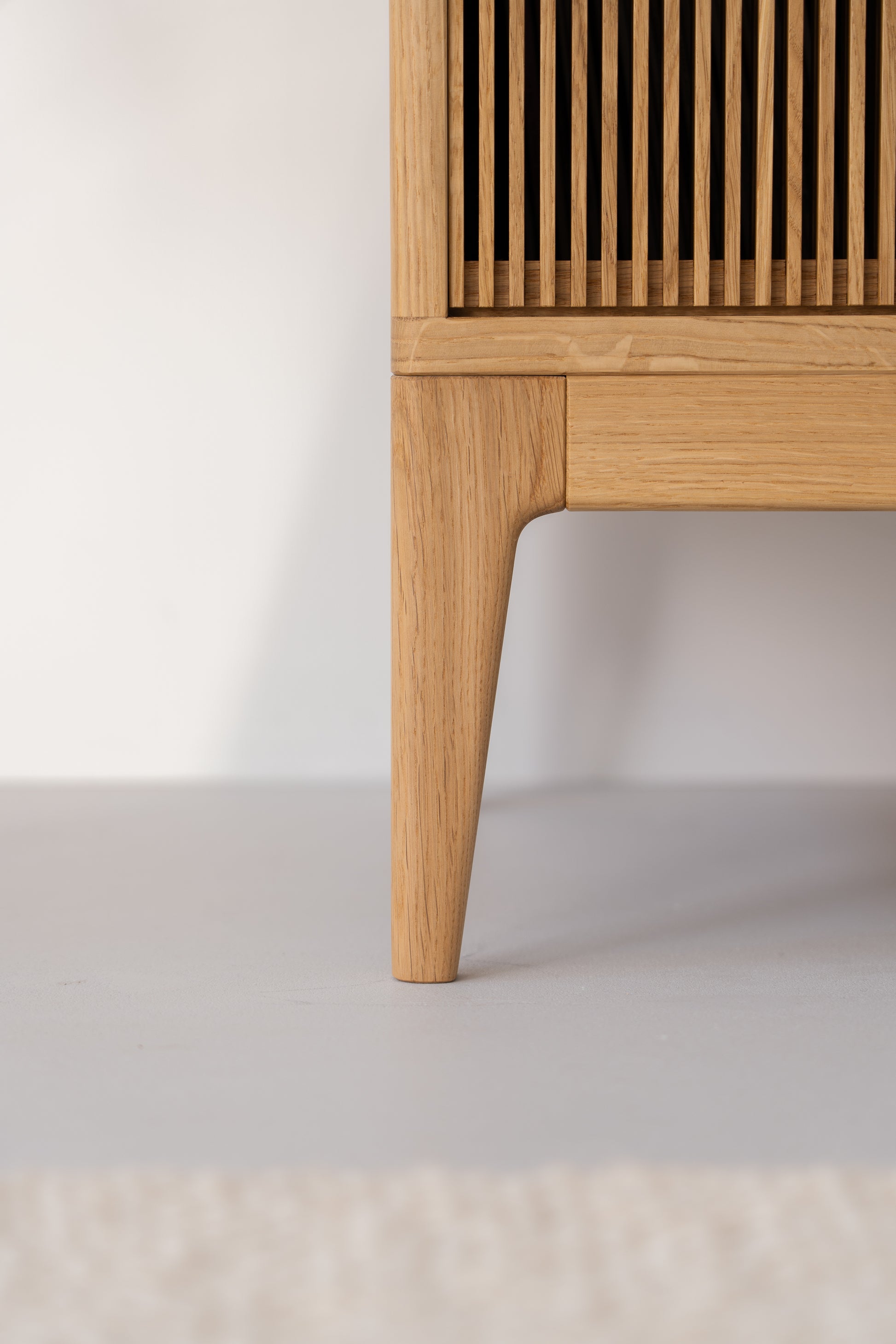 Close-up of wooden furniture leg with slatted design.