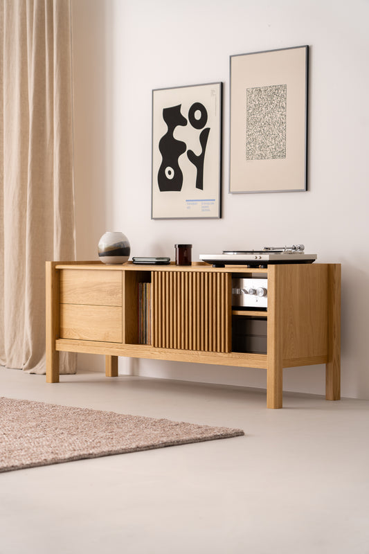 Modern wooden sideboard with decor items and abstract wall art, beside beige curtains and a textured rug.