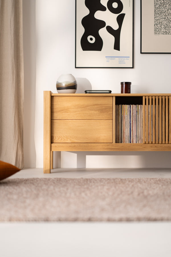 Minimalist wooden cabinet with decor, vinyl records, and framed artwork hanging on the wall.