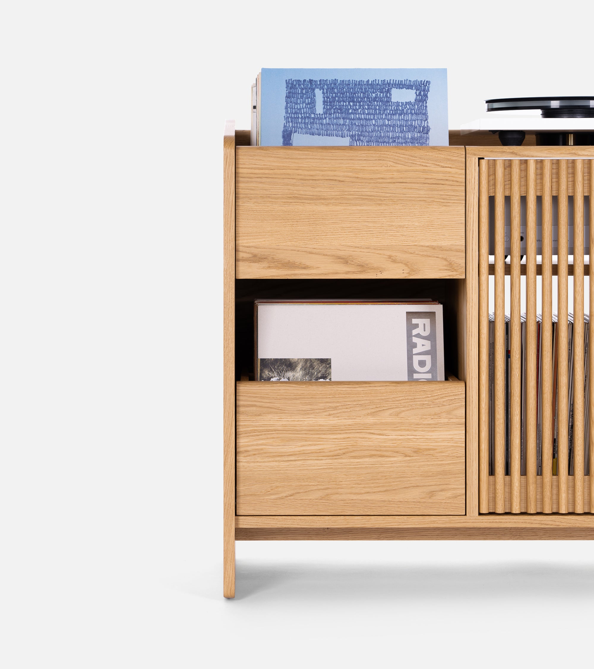 Wooden cabinet with open and slatted shelves, storing books and records.