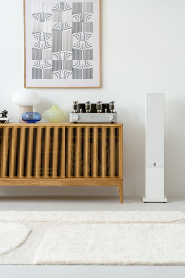 Modern living room with wooden cabinet, decorative vases, lamp, and framed abstract art on the wall.