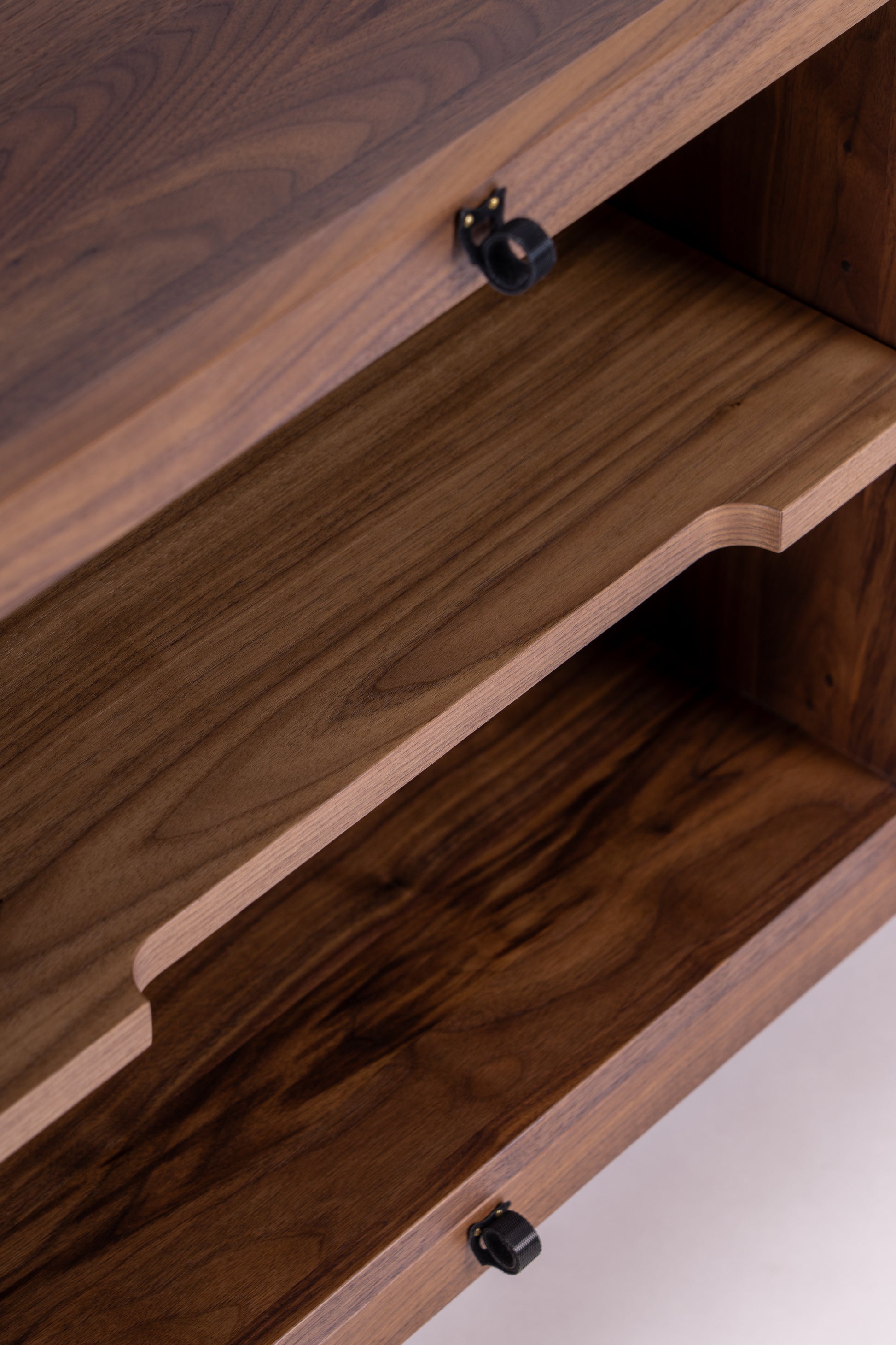 Close-up of a wooden cabinet with an open drawer, displaying smooth wood grain and black knobs.