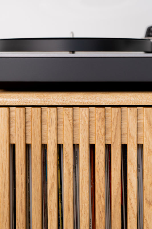 Close-up of a vinyl record player on a wooden cabinet with vertical slats.