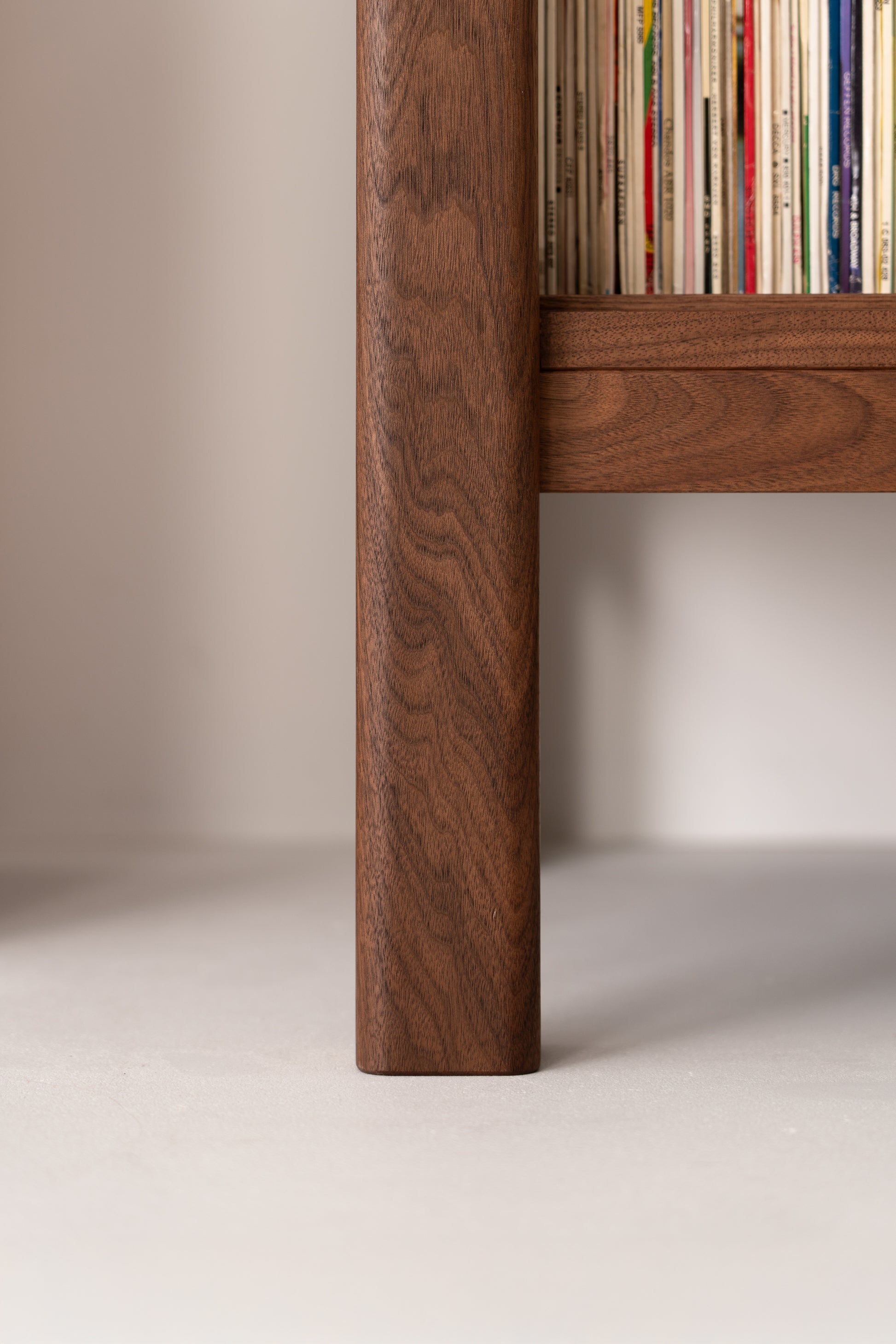 Close-up of a wooden shelf leg and a row of vertically stacked magazines.