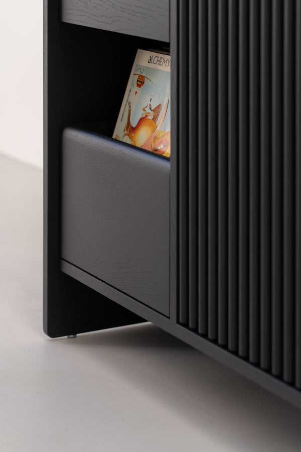 A close-up of a dark wooden shelf unit with a partially visible record titled "Alchemy" stored inside.