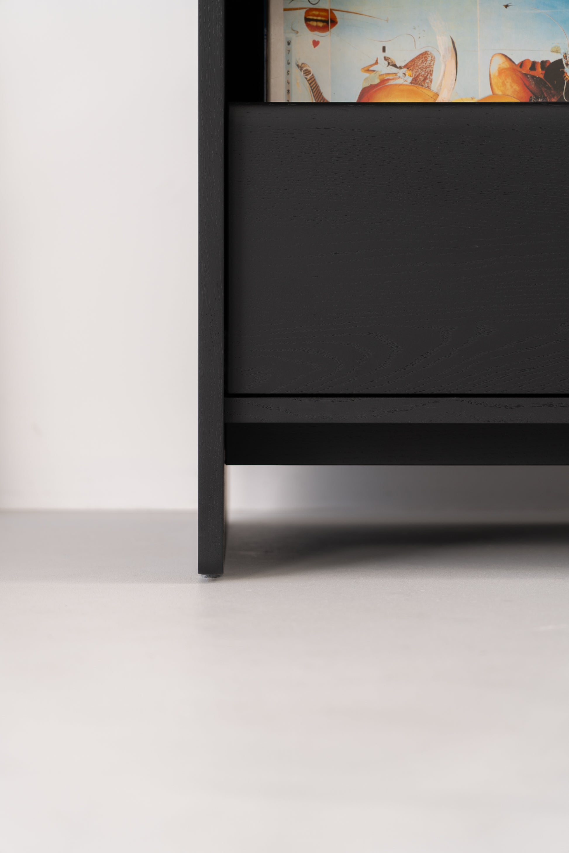 Close-up of the bottom section of a black wooden shelf, with visible books above.