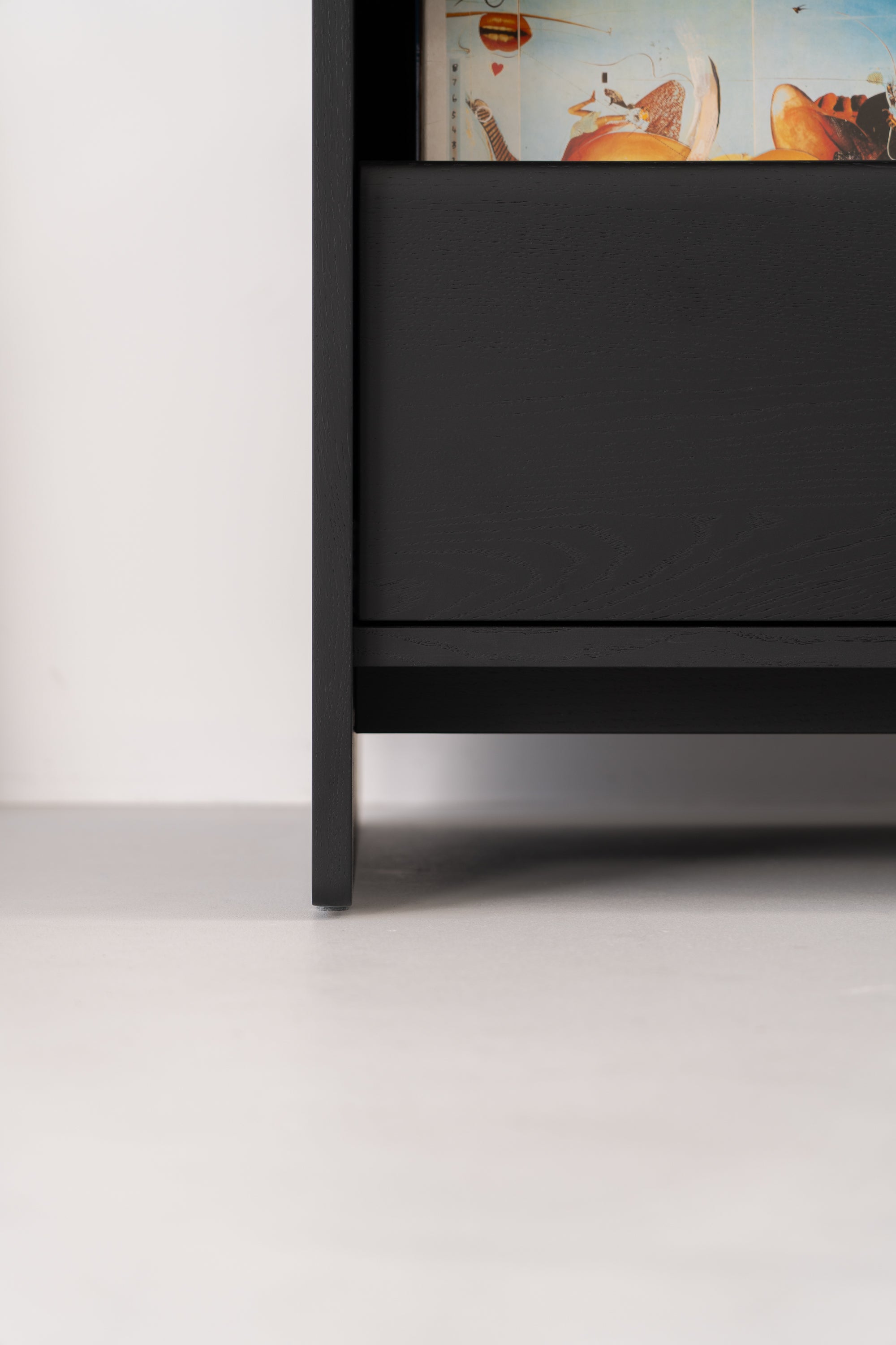 Close-up of the bottom section of a black wooden shelf, with visible books above.