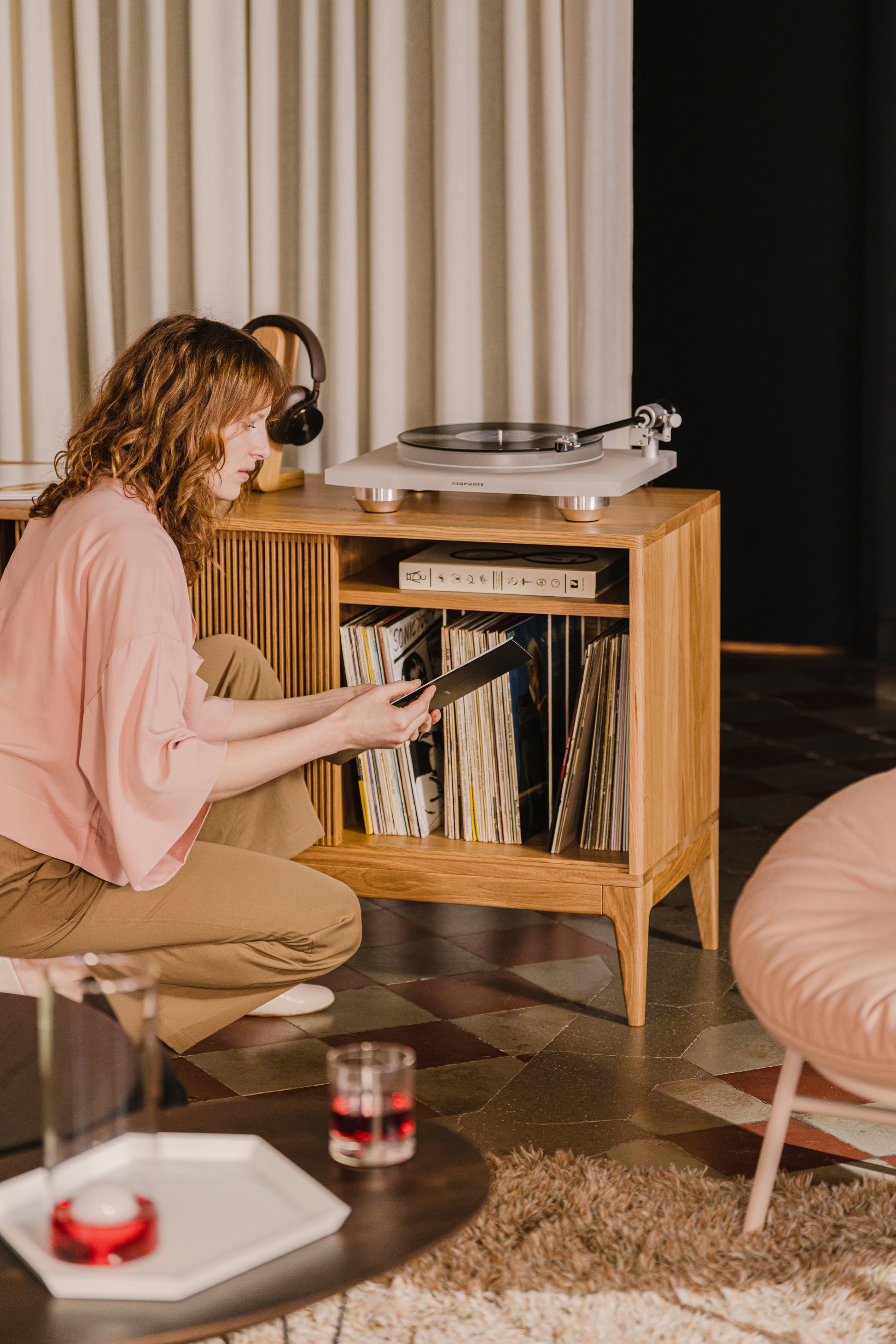 Person selecting a record from a wooden cabinet with a turntable on top.
