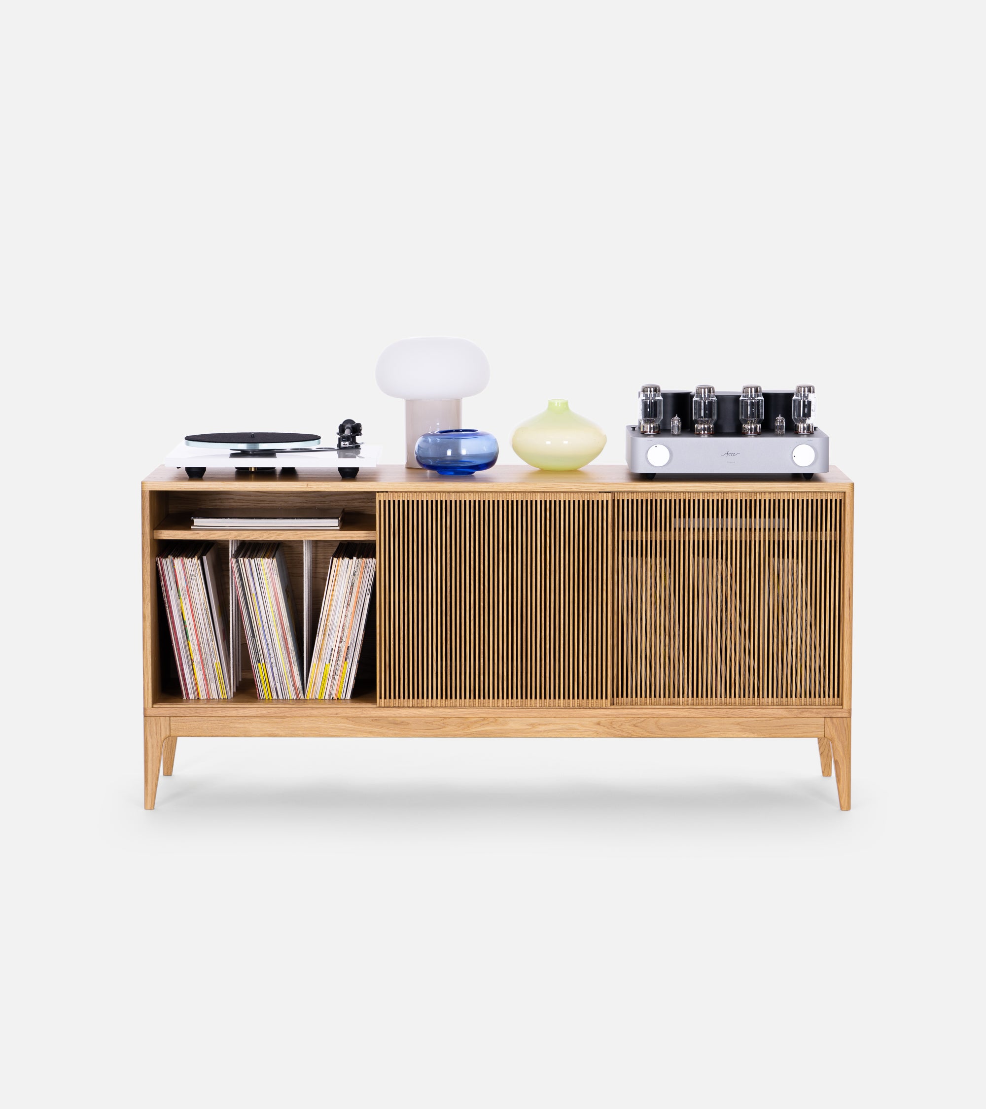 Wooden cabinet with vinyl records, turntable, lamps, vases, and an audio amplifier on top.