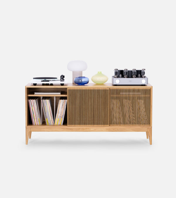 Wooden cabinet with vinyl records, turntable, lamps, vases, and an audio amplifier on top.