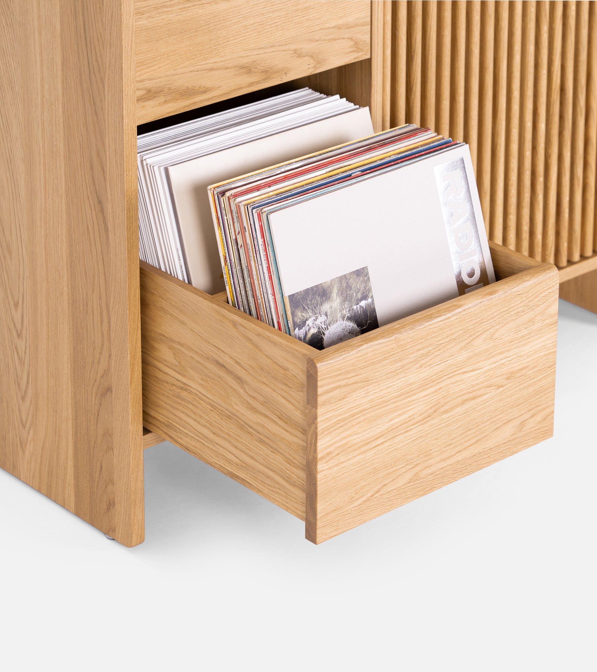 Wooden media console with a turntable, amplifier, and storage boxes on its shelves against a white background.