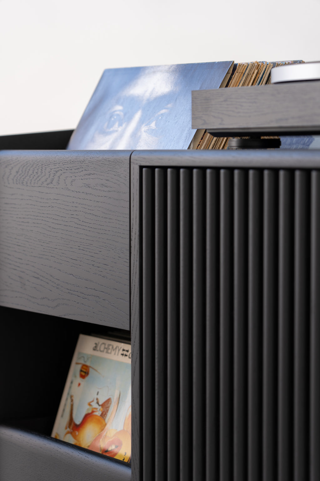 A black shelf with vinyl records, visible album covers, and a detailed wood texture.
