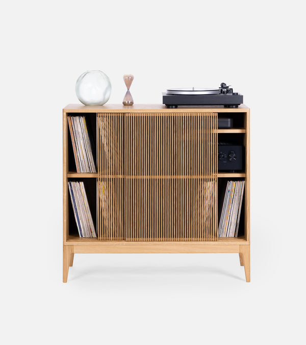 Close-up of the corner of a wooden table with blurry items on top in the background.