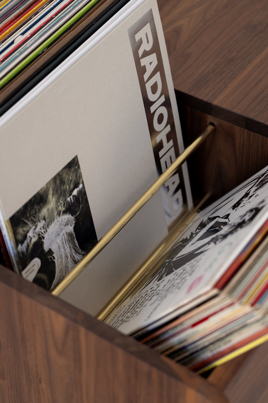 Close-up of a wooden record holder with various vinyl records, including one with "RADIOHEAD" on the cover.