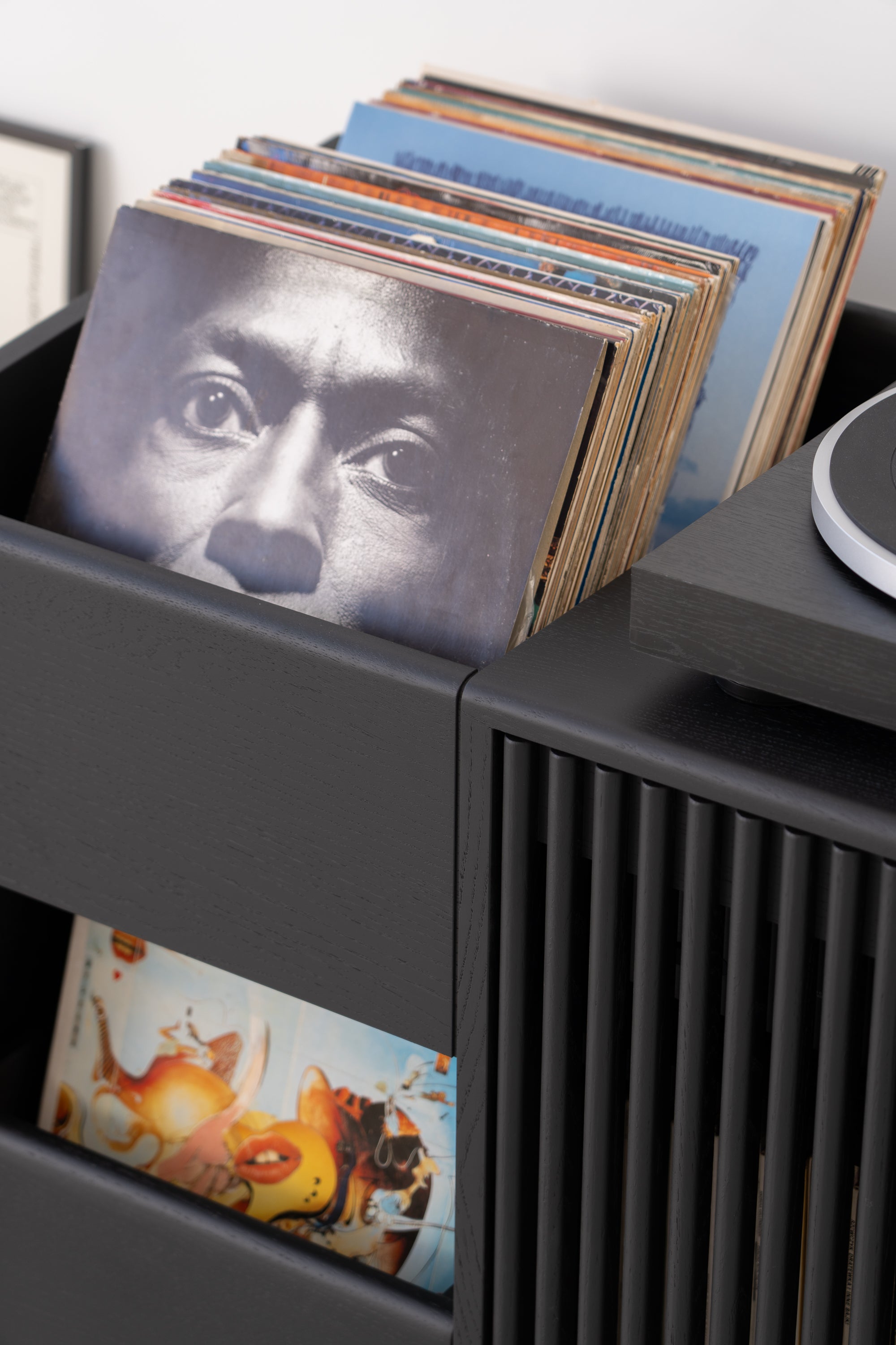 A stack of vinyl records in a black wooden storage unit.