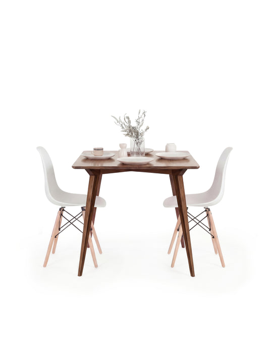 Wooden table with white chairs, small vase with flowers, and minimal decor on top.