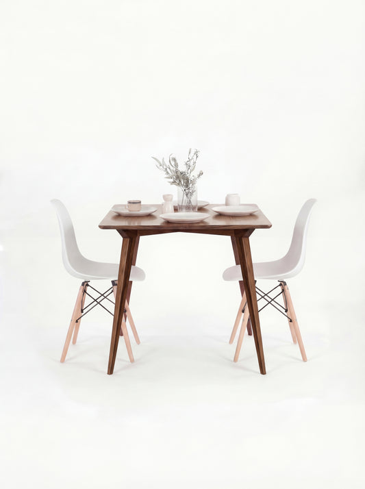 Wooden table with white chairs, small vase with flowers, and minimal decor on top.