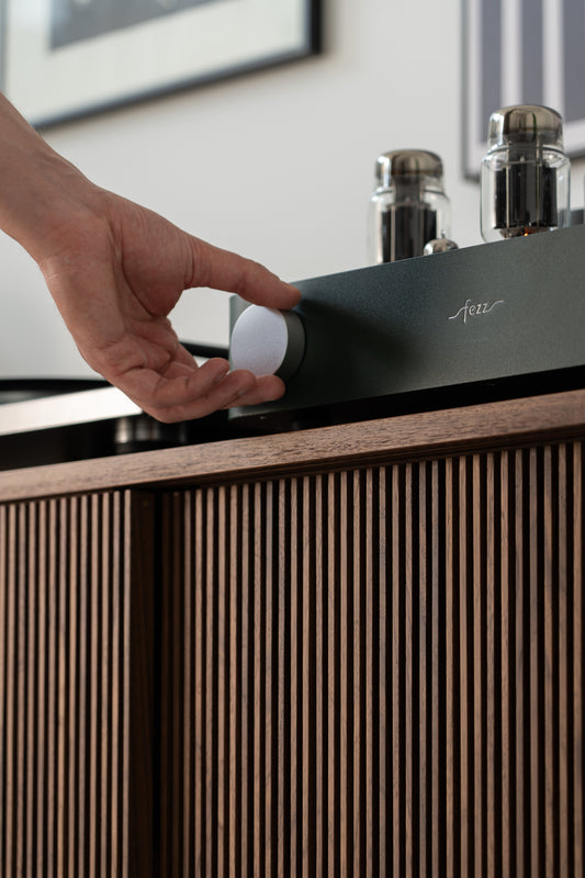 Hand adjusting the volume knob on a vintage tube amplifier.