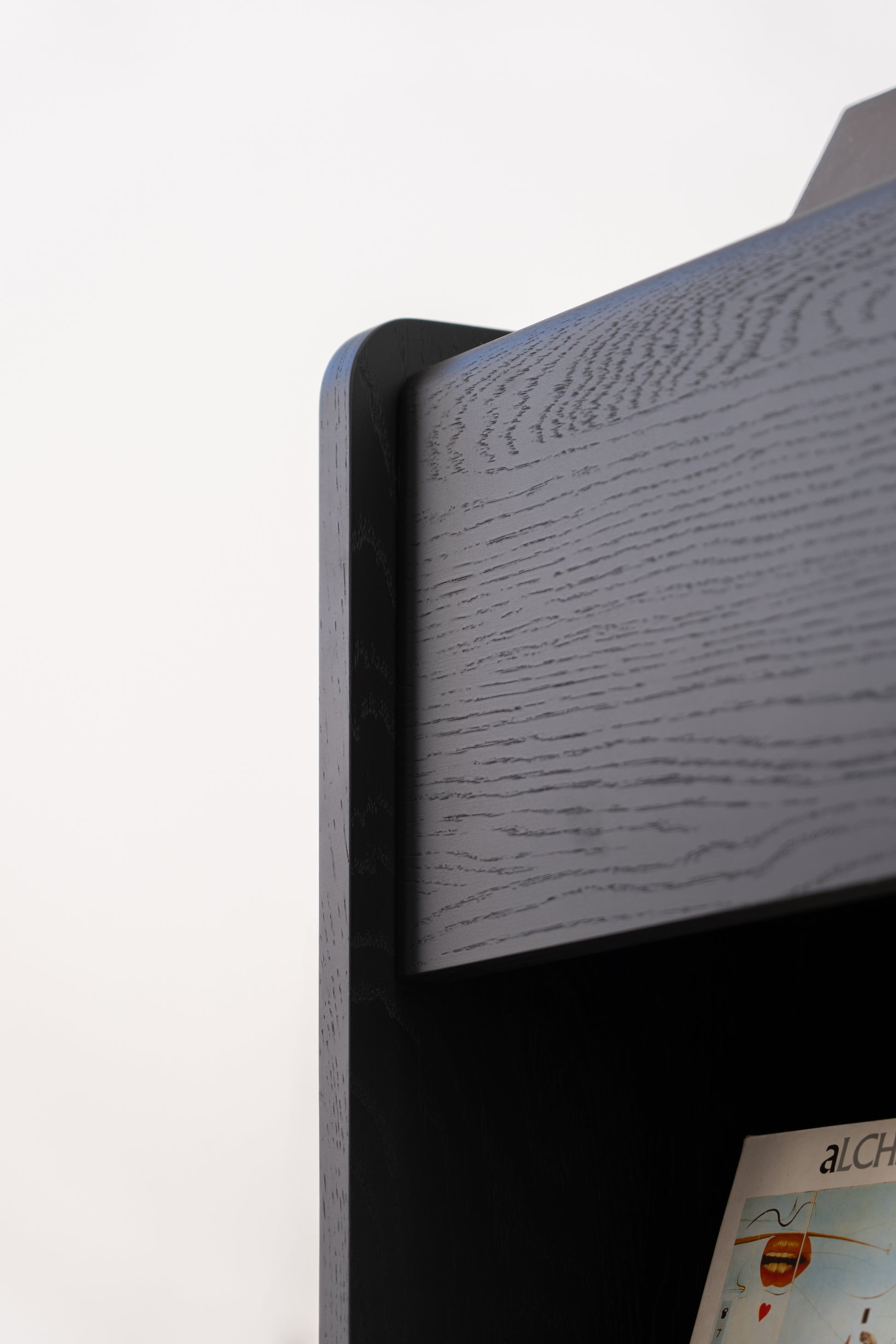 Close-up of the corner of a modern, black wooden bookshelf with a vinyl record visible on the lower shelf.
