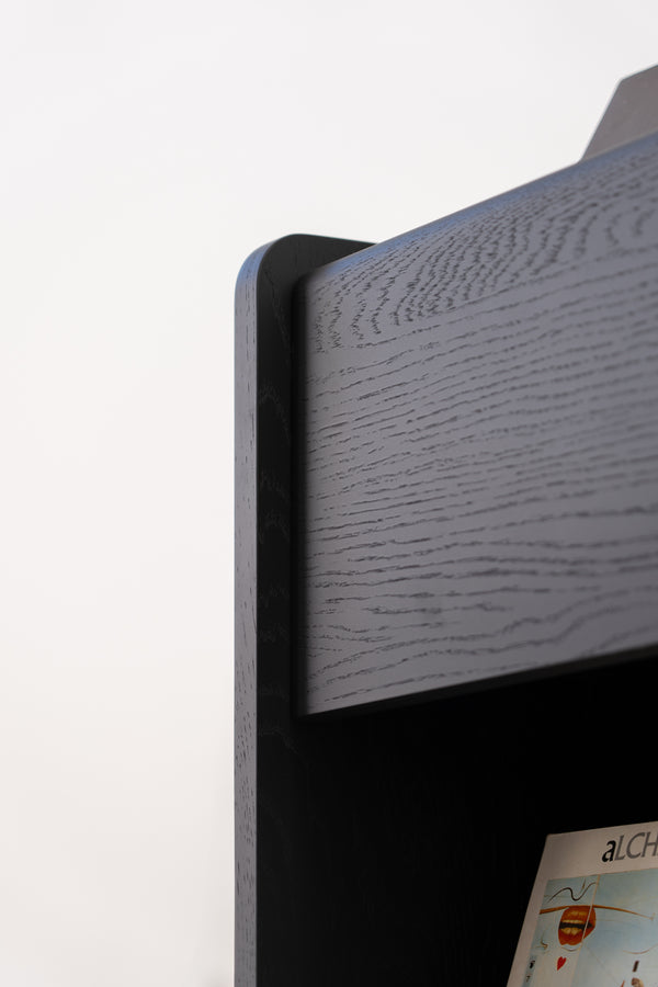 Close-up of the corner of a modern, black wooden bookshelf with a vinyl record visible on the lower shelf.