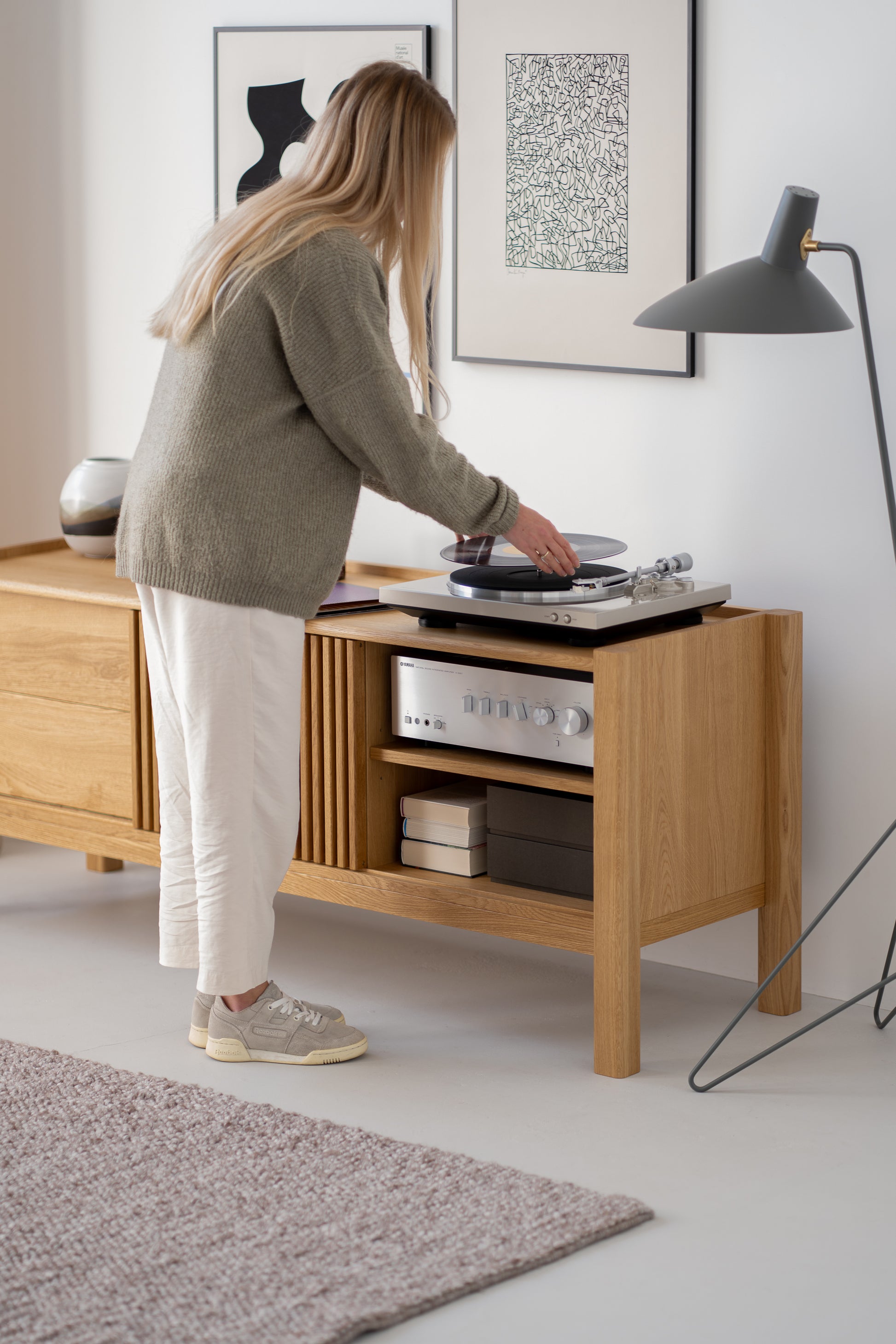 Person placing a vinyl record on a turntable in a modern living room.
