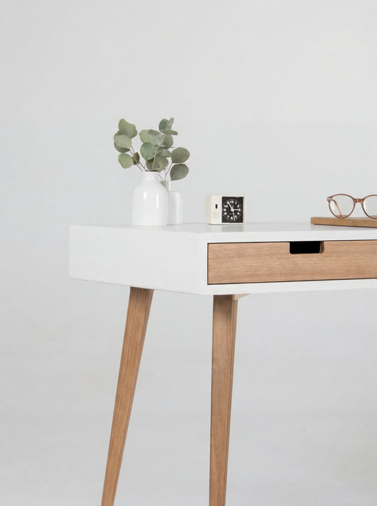 Close-up of the HEIM 140 desk in oak wood, showing its white body corner, oak drawer front and cut-out grip