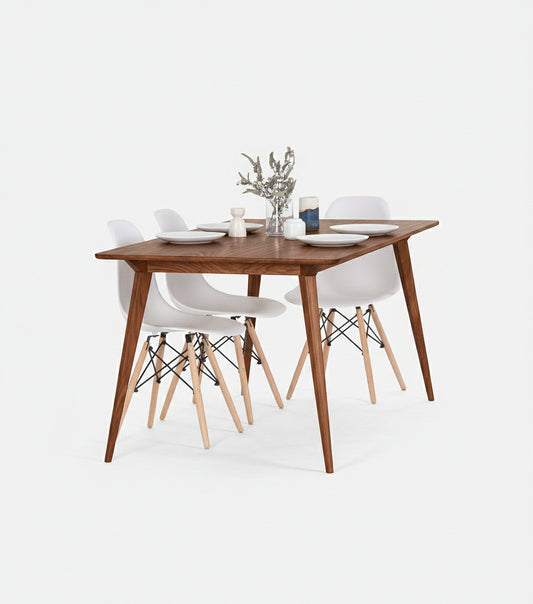 Wooden dining table with four white chairs, set with plates and a small plant centerpiece.