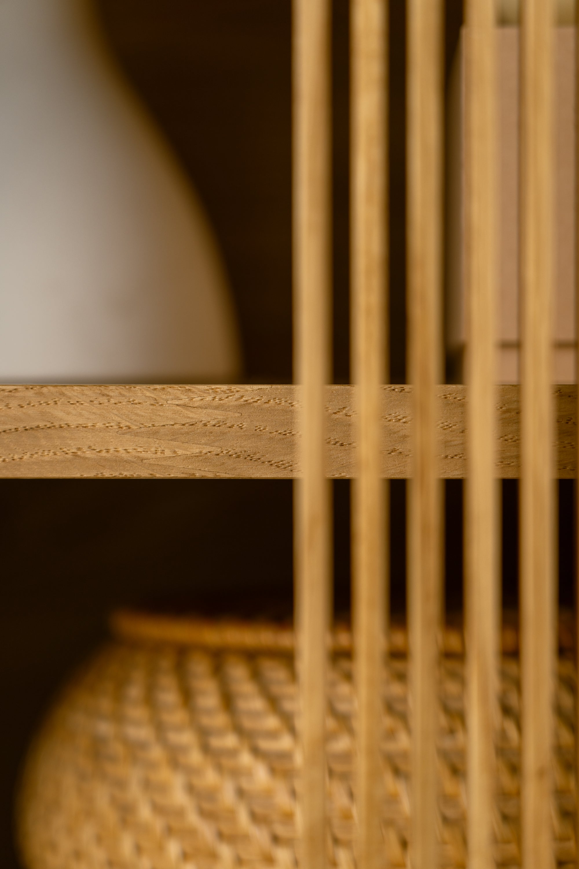 Close-up of wooden slats with a blurred background featuring a vase and wicker basket.