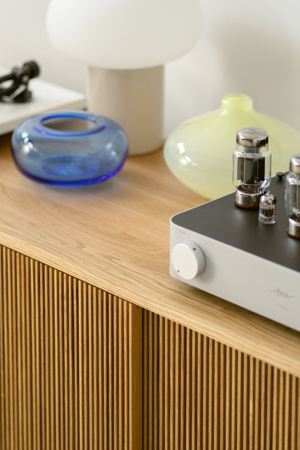 A wooden sideboard with decorative glass vases and a tube amplifier on top.