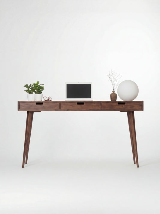 HEIM 140 wooden desk with drawers in walnut wood, shown from the front with a laptop and globe lamp