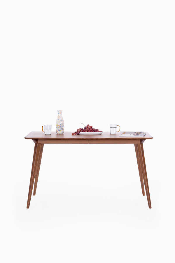 Wooden table with water glasses, grapes, and a magazine on a white background.