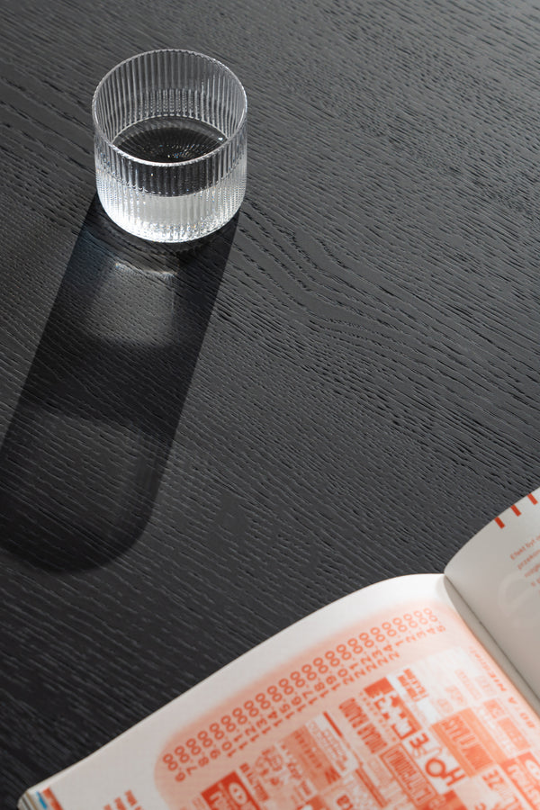 Close-up of the black oil-wax finish on the NOON coffee table surface with visible oak grain