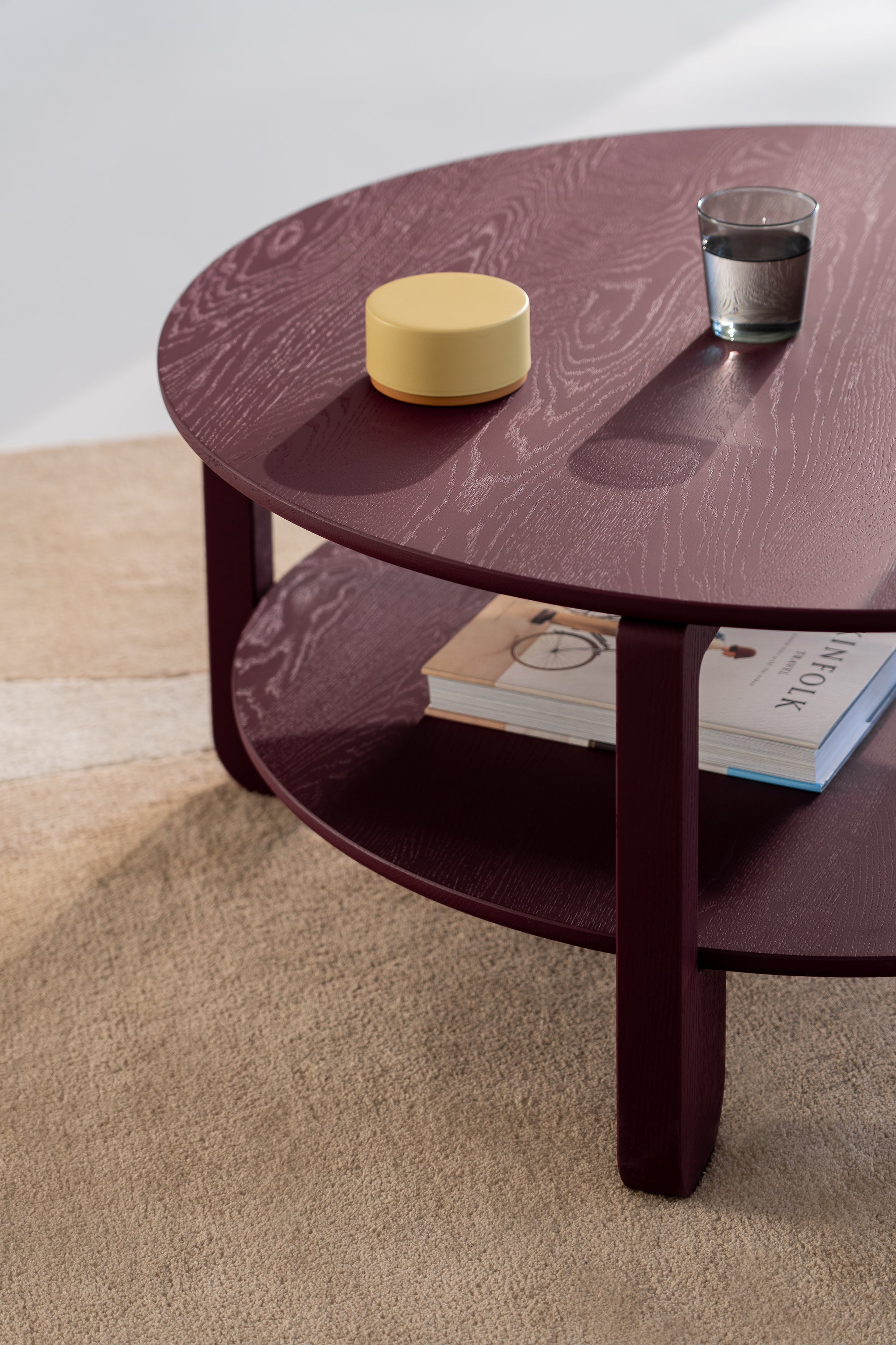 Edge detail of the NOON round tabletop showing the smooth burgundy oil-wax finish on oak