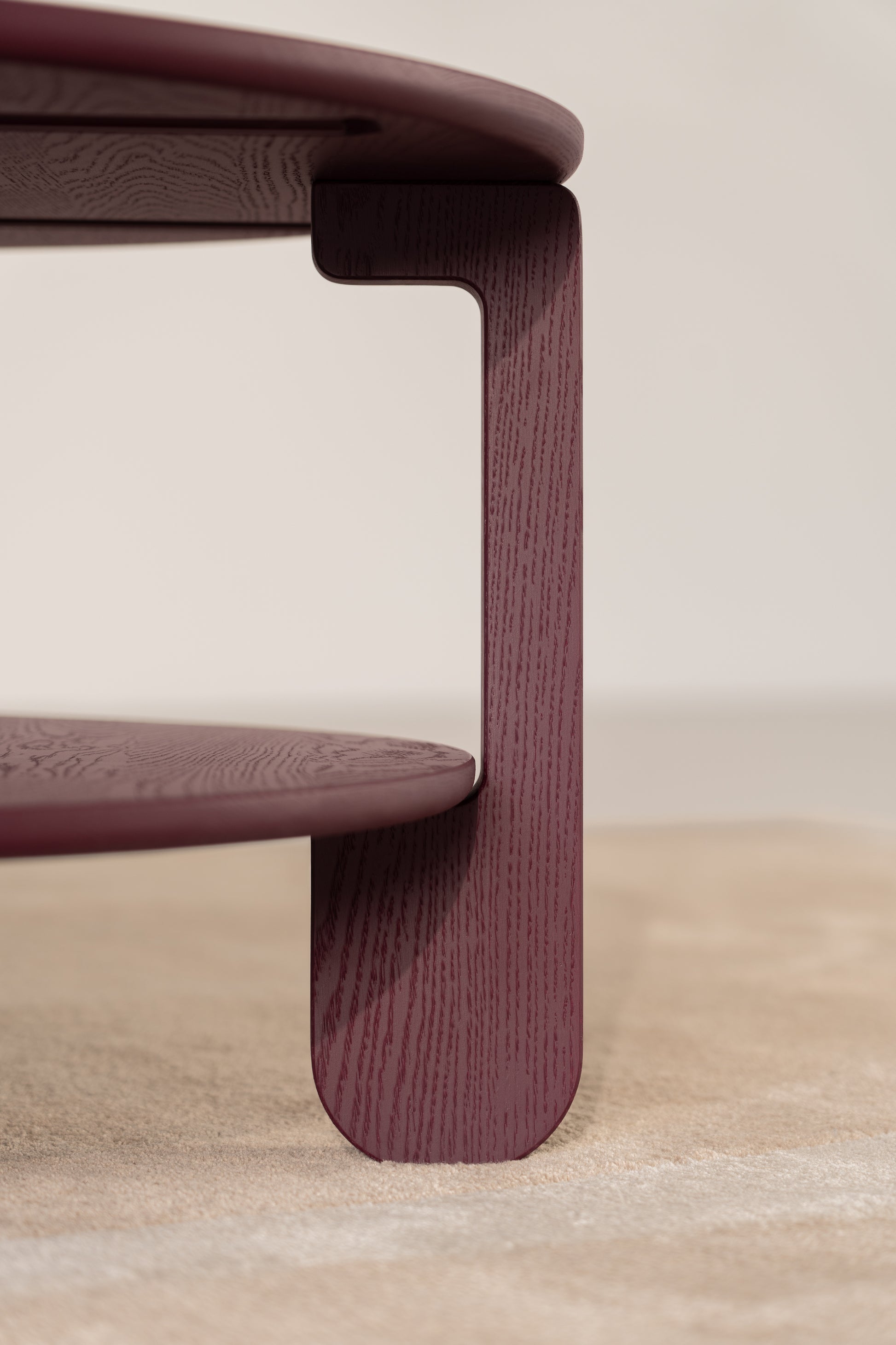 NOON burgundy table in a dimly lit room with warm light reflecting off the matte surface