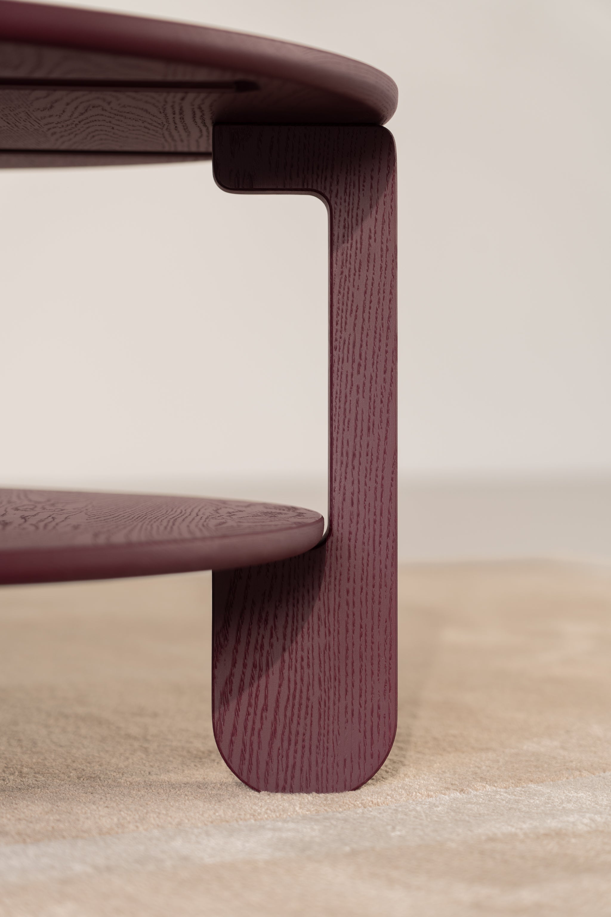 NOON burgundy table in a dimly lit room with warm light reflecting off the matte surface