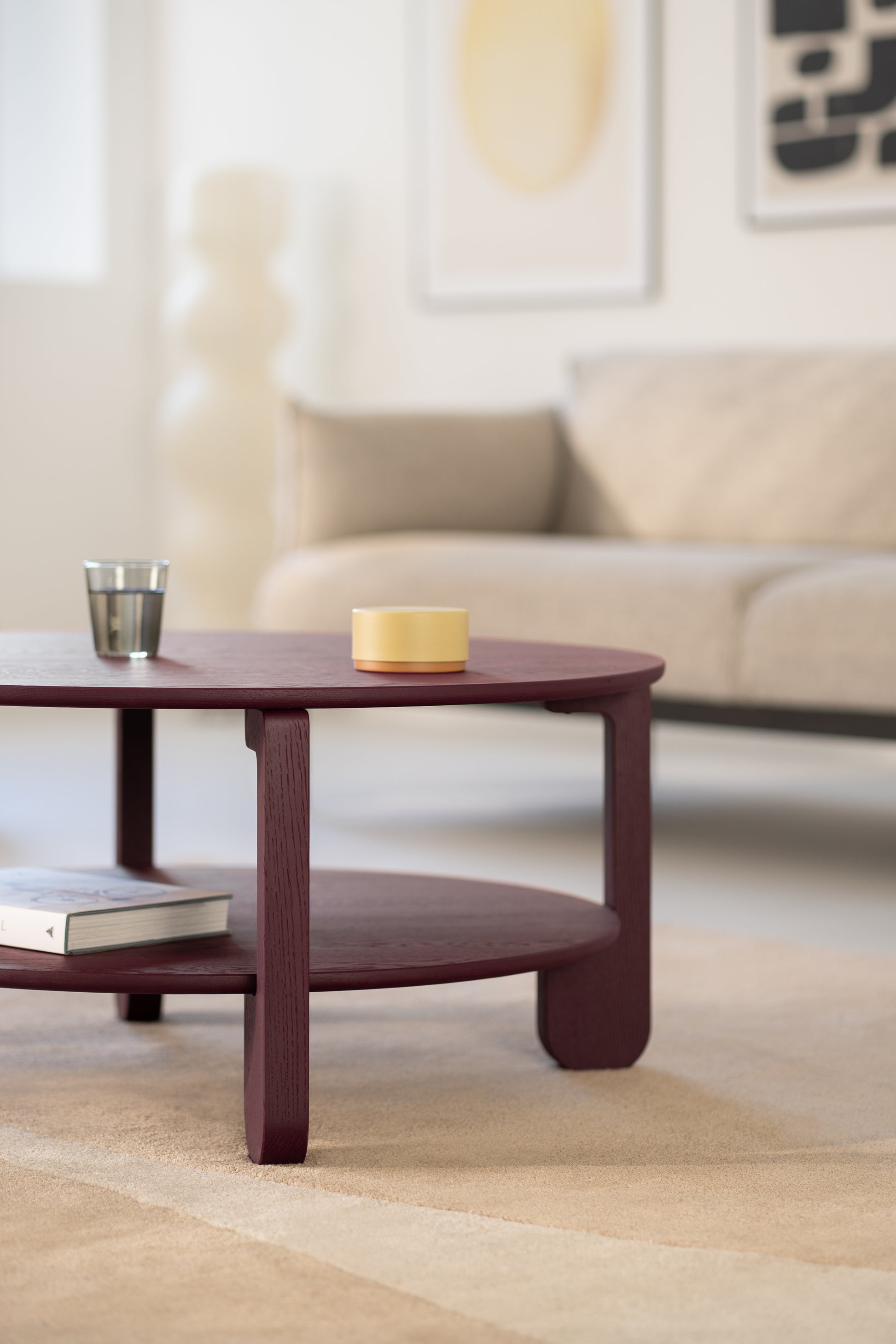 Full room view with the NOON round coffee table as the center piece on a pale area rug