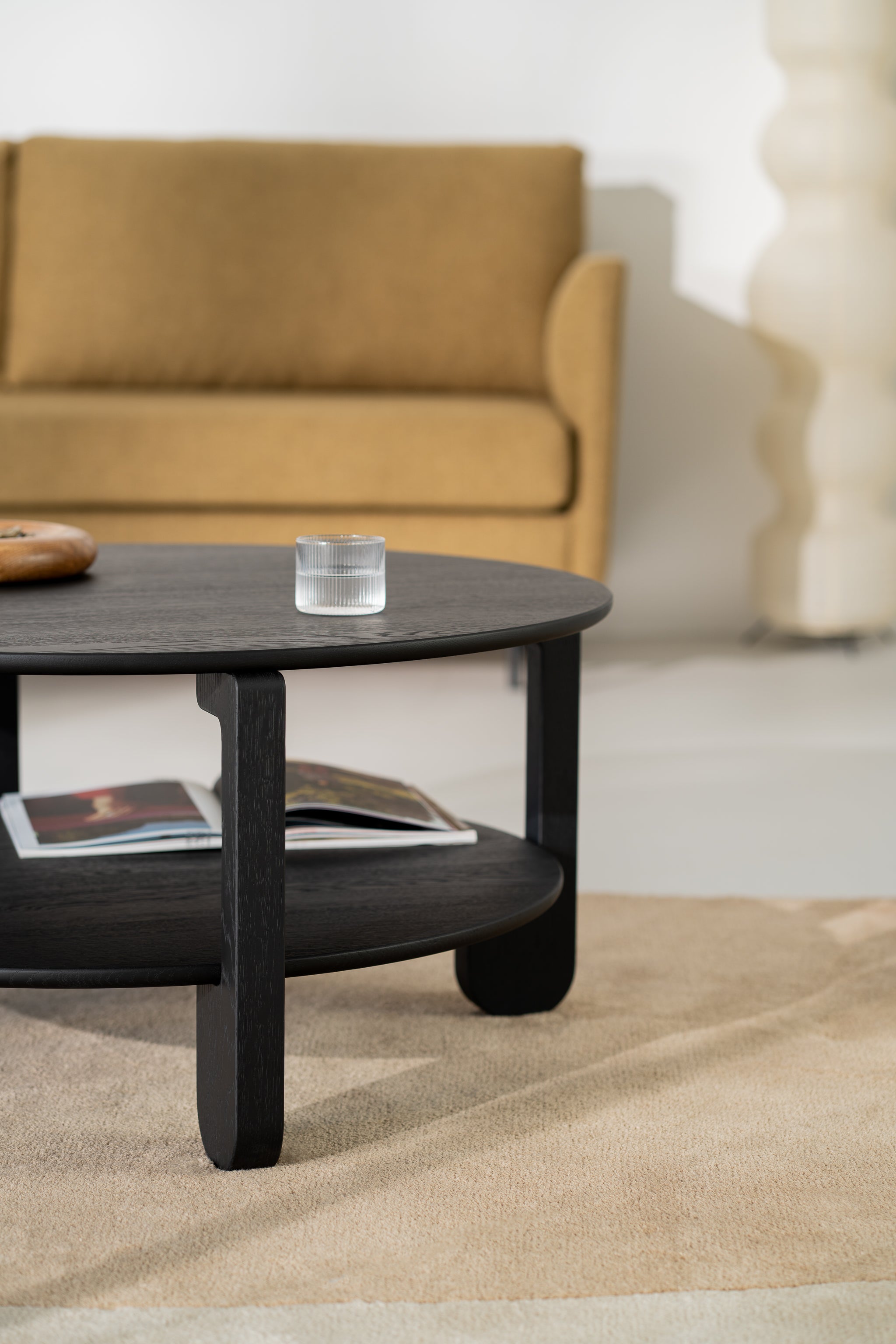 NOON round table with a ceramic vase and book on top, seen from a seated angle