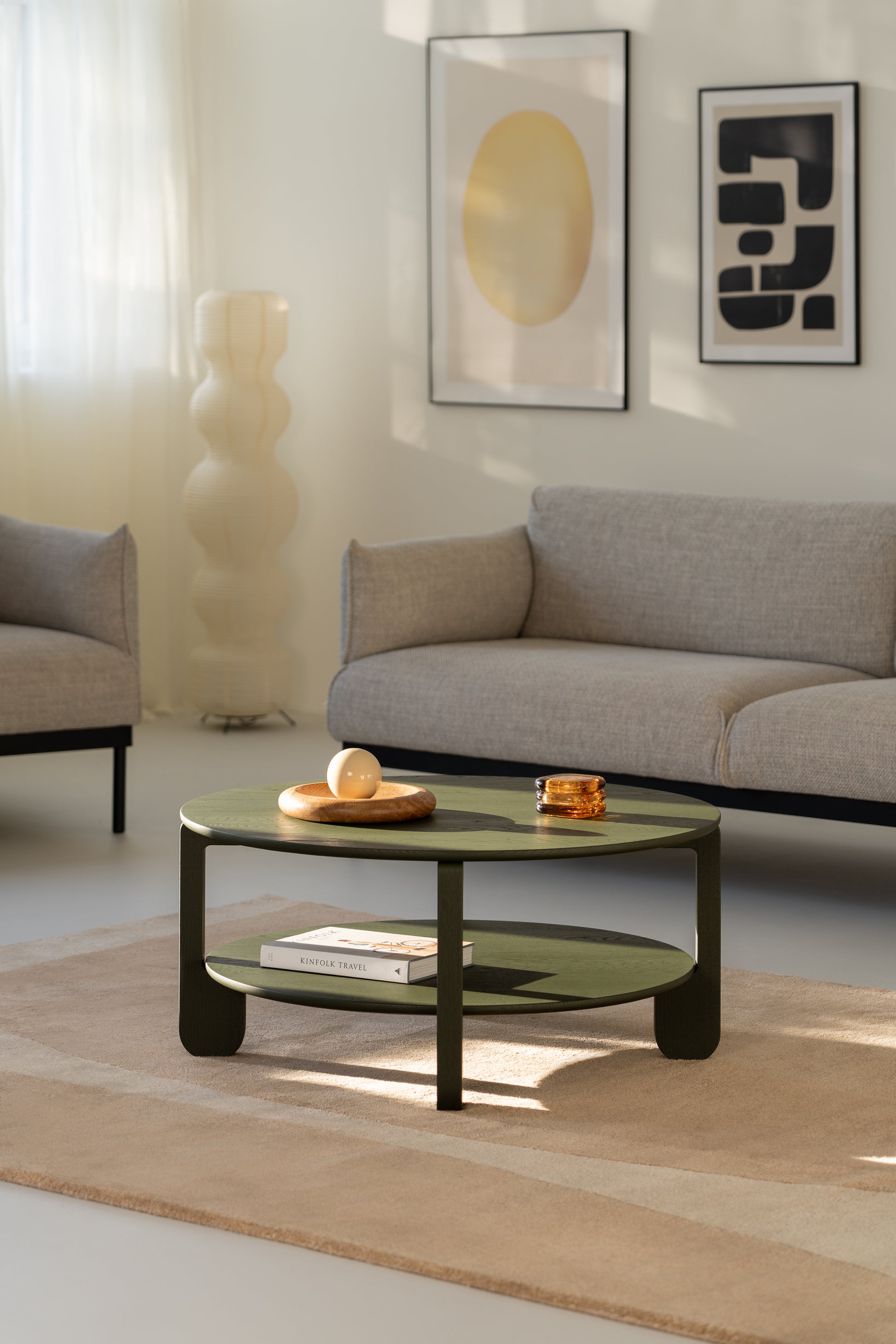 Full room shot with the NOON dark green round coffee table as a focal point on pale flooring