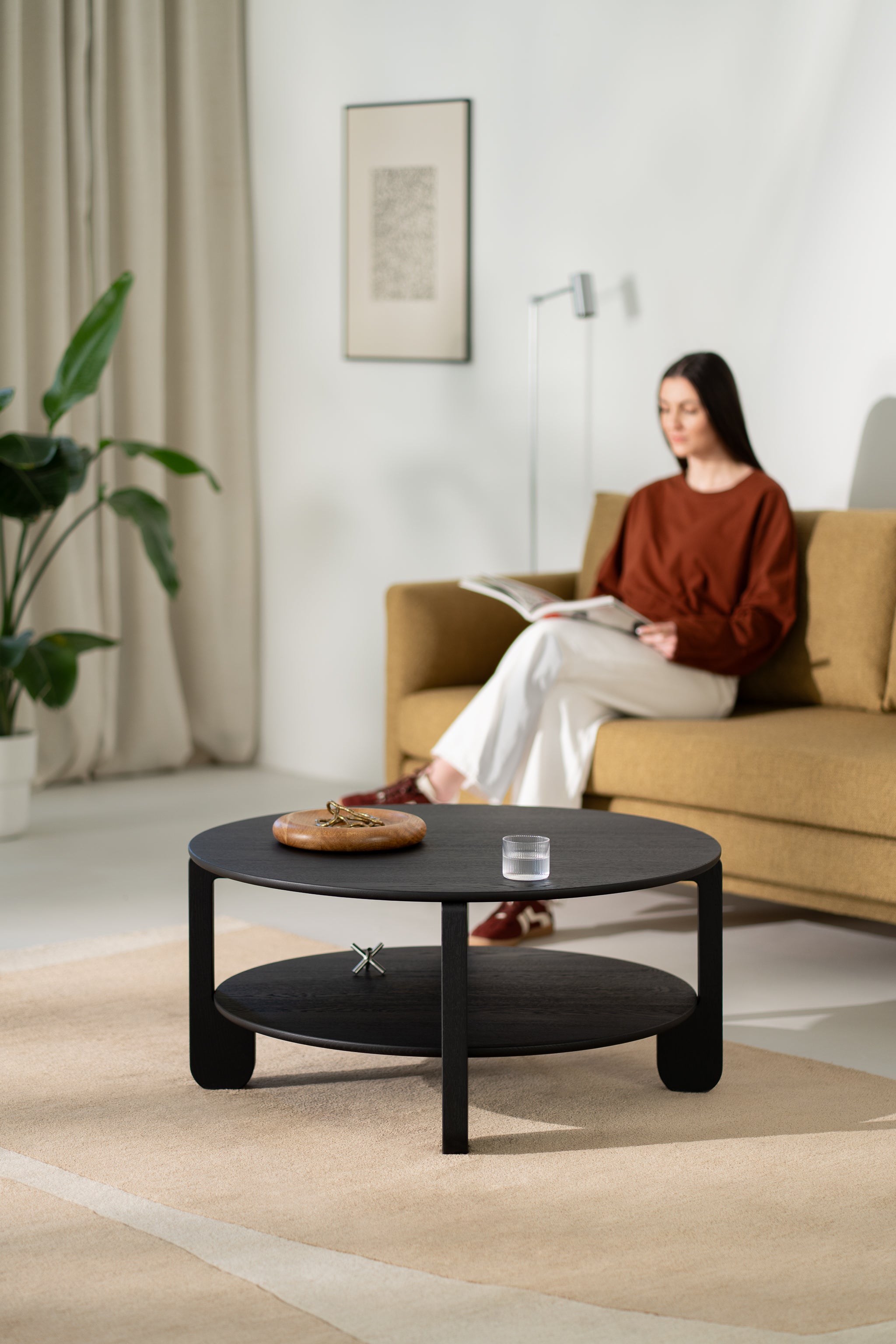 NOON round coffee table in black-finished solid oak on a light wooden floor
